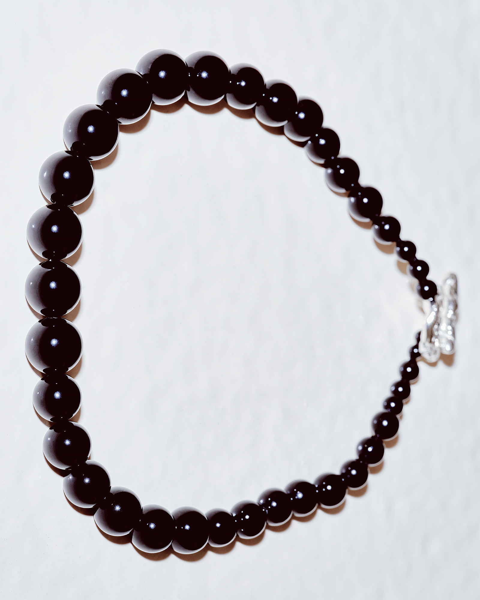 Studio shot of a deep brown pearl necklace arranged in a gentle curve. 