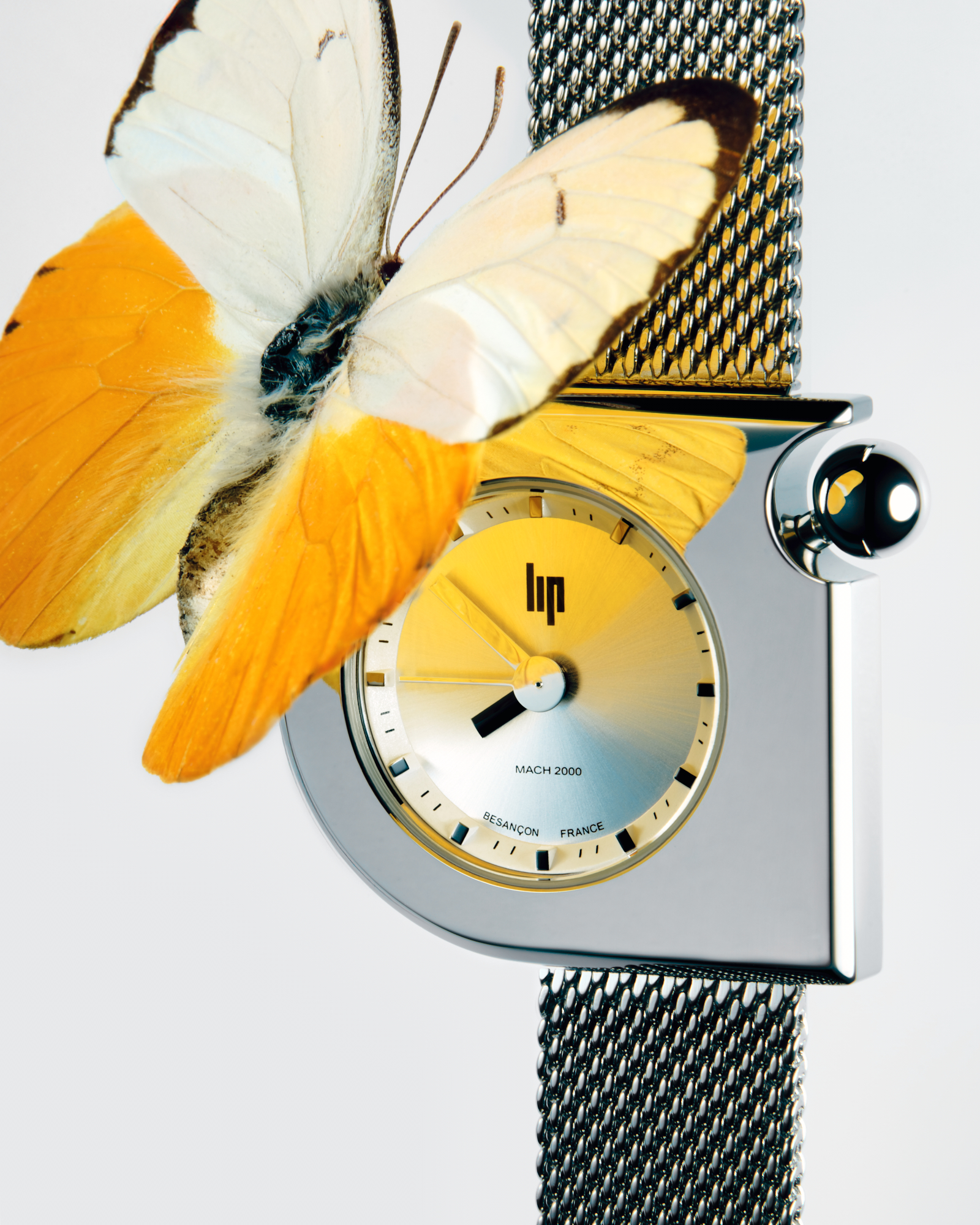 Lip-branded watch with silver mesh strap and a yellow-white butterfly resting on the face. 